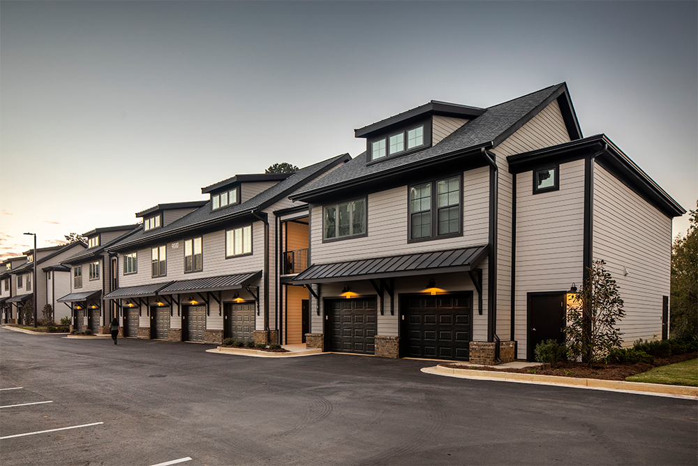 Row of modern townhouses with attached garages and driveway, photographed at dusk under a clear sky—an example of market rate developments shaped by expert multifamily general contractors.